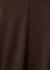 Pantalón de punto color marrón oscuro, de tiro medio, cintura con goma elástica y diseño recto y largo. Cuenta con detalle de costuras verticales.