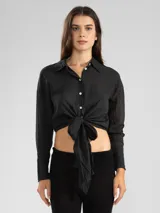 Camisa negra de manga larga con lazo en la cintura y botones nacarados. Confeccionada en 100% algodón y detalle de Polonio en cobre.