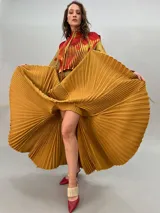 Vestido largo plisado con estampado abstracto en tonos rojo, naranja y dorado, cuello alto y mangas acampanadas. Incluye lazo fino para ajustar en la cintura.