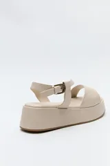 Sandalia negra con plataforma, tiras cruzadas sobre el empeine y pulsera ajustable al tobillo.