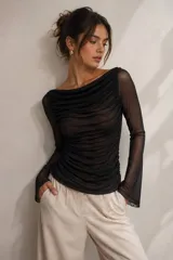 Blusa de tul transparente color gris, con diseño drapeado en todo el cuerpo, escote bote y mangas largas.