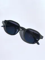 Lentes de sol con armazón de marco completo en color gris mate, con detalles decorativos en color rojo en las esquinas y patillas. Cuentan con cristales oscuros polarizados con protección UV 400.