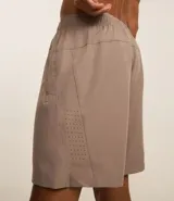 Bermuda deportiva gris con cintura elástica, cordón de ajuste, bolsillos con cremallera, recorte lateral con agujeritos y abertura en el bajo.