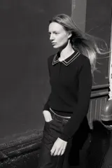 Jersey de punto color azul marino, de manga larga, con cuello polo y cierre frontal de botones. Presenta vivos blancos con borde ondulado en el cuello, puños y ruedo inferior.