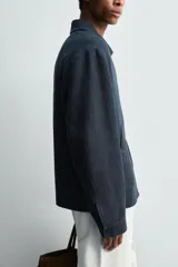 Cazadora regular fit color azul marino, confeccionada en tejido de lino con efecto ligeramente lavado. Presenta cuello solapa, manga larga con puño abotonado, bolsillos de vivo en la cadera y un bolsillo interior. Cierre frontal con cremallera.
