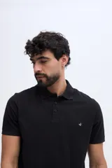 Remera polo verde militar de algodón pima, con cuello y puños acanalados, cierre frontal de tres botones y pequeño bordado de ave en el pecho.