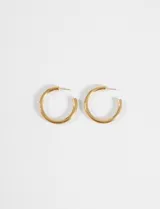 Aros tipo argolla de diseño curvo y minimalista, fabricados en acero quirúrgico con acabado dorado.
