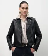 Campera estilo biker confeccionada en poliuretano con acabado liso. Presenta cierre frontal asimétrico con cremallera metálica, cuello con solapas, mangas largas con cremalleras en los puños y corte entallado.