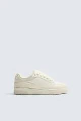 Zapatilla deportiva estilo basket con cordones gruesos, confeccionada en una combinación de piezas en tonos crema y beige, con suela de goma con volumen.