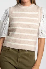 Chaleco de punto sin mangas con diseño de rayas horizontales en tonos beige y blanco, cuello redondo y terminaciones acanaladas.