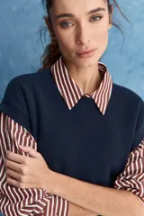 Chaleco de tejido de punto color beige claro, con cuello redondo y diseño de líneas limpias con hombros caídos y terminaciones acanaladas.