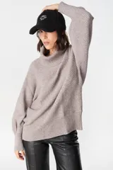 Sweater de punto con textura acanalada, cuello alto tipo polerón, mangas largas con diseño abuchonado y puños anchos.