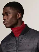 Campera bomber negra con frente acolchado y mangas de tejido liso. Cuello, puños y bajo de punto canalé. Cierre frontal con cremallera. Logo de Tommy Hilfiger bordado en el pecho.