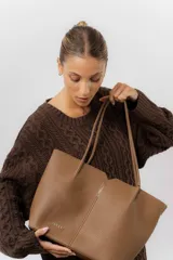 Cartera tipo tote de diseño amplio y estructurado, confeccionada en material sintético con textura graneada. Cuenta con doble asa larga para llevar al hombro y logo de la marca aplicado en el frente.