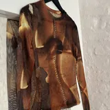 Top de microtul con estampado abstracto en tonos marrones. De manga larga y cuello redondo.