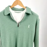 Sweater de punto verde con cuello polo y cierre de cremallera parcial.