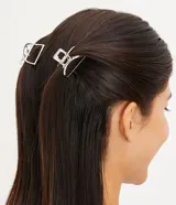 Set de dos pinzas para el pelo plateadas con forma de media luna.
