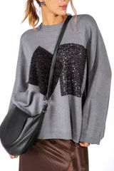 Sweater de punto color blanco con diseño de parches geométricos en contraste negro en el frente. Presenta cuello redondo, mangas largas con hombros caídos y terminaciones en tejido acanalado.