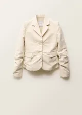 Blazer de corte recto y diseño estructurado, confeccionado en una mezcla de algodón y lino. Presenta cuello con solapas de muesca, cierre frontal con botones, mangas largas con puños abotonados y dos bolsillos laterales con solapa. Incluye forro interior y abertura posterior en el bajo.