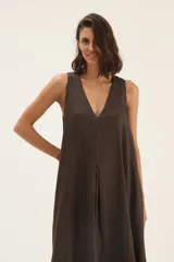 Vestido largo color crudo, de lino, con escote en V, corte acampanado y bolsillos laterales.