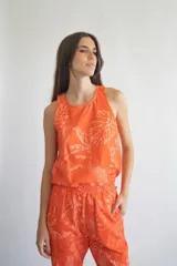 Musculosa naranja con estampado de hojas y animales en tonos claros, de corte recto y cuello redondo.