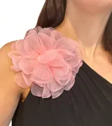 Broche en forma de flor grande confeccionado en organza rosada, con sistema de sujeción versátil para prendas o cabello.