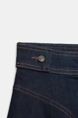 Falda corta de tiro medio confeccionada en tejido denim de algodón. Presenta un diseño acampanado con costuras a contraste, cintura con botones metálicos y cierre frontal con cremallera y botón.