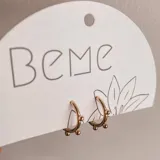 Aros dorados tipo argolla con tres bolitas decorativas.