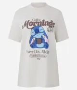 Remera de algodón color crema con cuello redondo y manga corta. Presenta un estampado frontal con el personaje Stitch sosteniendo una taza de café y la leyenda 'Coffee Mornings Club'.