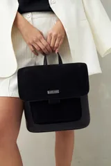 Mochila estructurada color marrón oscuro, con frente en acabado gamuzado y cuerpo en símil cuero texturizado. Tiene asa superior y correas regulables.