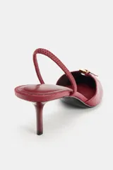 Zapato destalonado de tacón fino, color bordó, con acabado en punta, detalle de hebilla metálica en la parte delantera y tira elástica trasera.