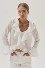 Blusa blanca de gasa con lunares, escote en V con volados y mangas largas acampanadas.