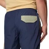 Pantalón cortavientos azul marino con tecnología Omni-Shield repelente al agua y manchas, bolsillos laterales con cierre y detalles en tono mostaza y verde.