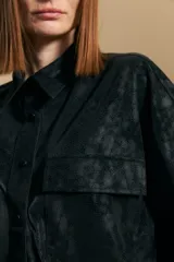 Sobrecamisa de efecto engomado en color negro, con textura lavada, cuello clásico, cierre frontal con botones a tono y bolsillos frontales con solapa.