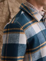 Chaqueta de lana con cierre frontal completo, diseño a cuadros en tonos azul marino y verde, cuello camisero y bolsillos laterales.