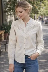 Camisa de lino color beige melange, con cuello mao, cierre frontal de botones y mangas largas. Presenta detalles de alforzas y aplicaciones de puntilla de algodón en el frente y en las mangas, con un diseño de silueta relajada.