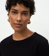 Suéter de punto ajustado con cuello redondo y manga larga. Presenta detalle de botones metalizados en los puños.