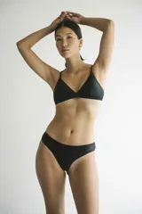 Top de bikini negro, de corte triangular clásico, con copas removibles y tirantes finos. Confeccionado en tejido italiano con filtro UV 50.