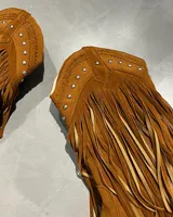 Botas texanas de gamuza color marrón, con flecos que cubren la caña y detalles de tachas plateadas en la parte superior.
