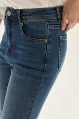 Jean de mezclilla azul de tiro medio, con silueta ligeramente acampanada desde la rodilla.