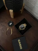 Reloj Casio Quartz con caja cuadrada y correa de eslabones en tono dorado. La esfera es de color negro con manecillas y marcadores de hora dorados, y cuenta con una ventana de fecha.