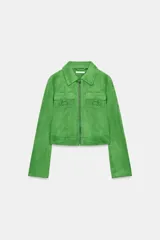 Chaqueta corta de tejido efecto ante en color verde vibrante, con cuello solapa, cierre frontal de cremallera y mangas largas. Presenta dos bolsillos frontales con solapa decorados con arandelas metálicas en el pecho.