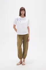 Remera blanca de manga corta y cuello redondo, con un bordado floral en tonos azules en la zona superior izquierda del pecho.