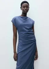 Vestido midi de color azul, con cuello drapeado, diseño sin mangas y detalle de drapeado en la cintura. Presenta un corte recto y cierre de cremallera lateral.