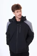 Campera técnica con capucha desmontable, diseño bicolor en negro y gris. Cuenta con cierre frontal termosellado, bolsillos laterales y bolsillo en el pecho con cierre, ideal para protección contra el viento y el frío.