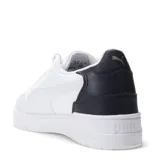 Championes urbanos Puma modelo Shuffle Downtown, color negro con detalles en dorado. Presentan una capellada de cuero sintético con perforaciones en la puntera, cierre de cordones y suela de goma vulcanizada.