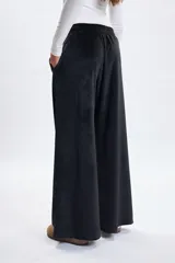 Pantalón deportivo de corte ancho confeccionado en tela plush negra, con detalle de nervio frontal y cintura elástica.