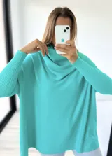 Polerón de punto color verde agua, con diseño mega oversize y cuello caído tipo polera. Presenta mangas largas con puños acanalados.