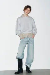 Bota estilo biker de caña media, confeccionada en cuero sintético negro. Presenta un diseño con tacón en bloque, punta cuadrada y detalle de doble tira con tachas metálicas y arandela en la zona del tobillo.