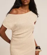 Blusa de punto color crema, con escote asimétrico, mangas cortas, textura y fruncido lateral.